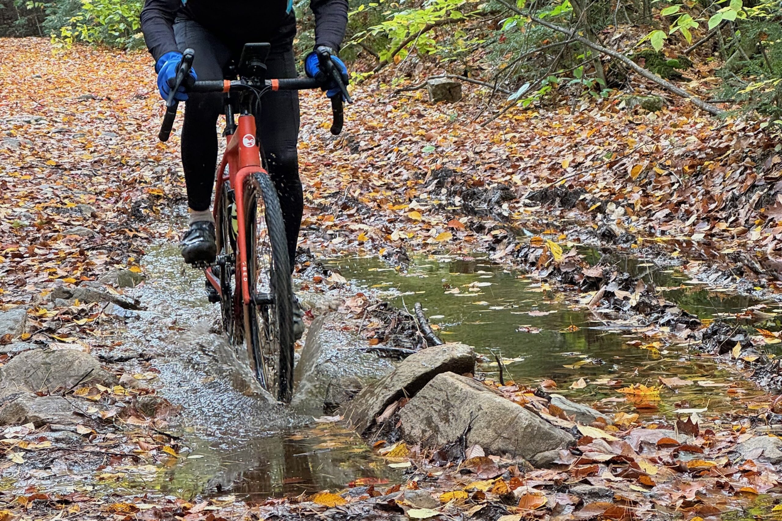 Riding through a puddle on a gravel bike in conditions that are best suited to a wet chain lube